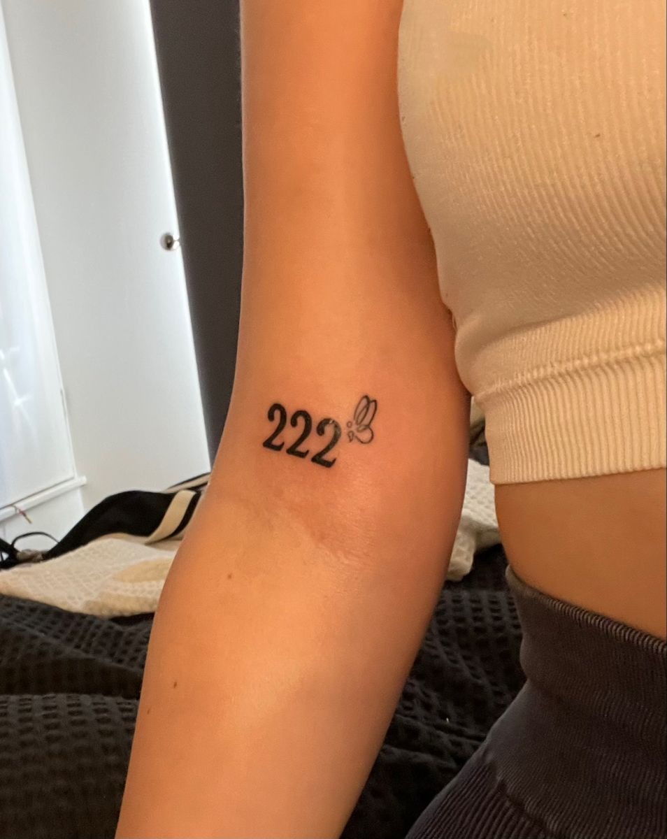 Mini Butterfly Beside 222, a tattoo design rendered in delicate fine-line.