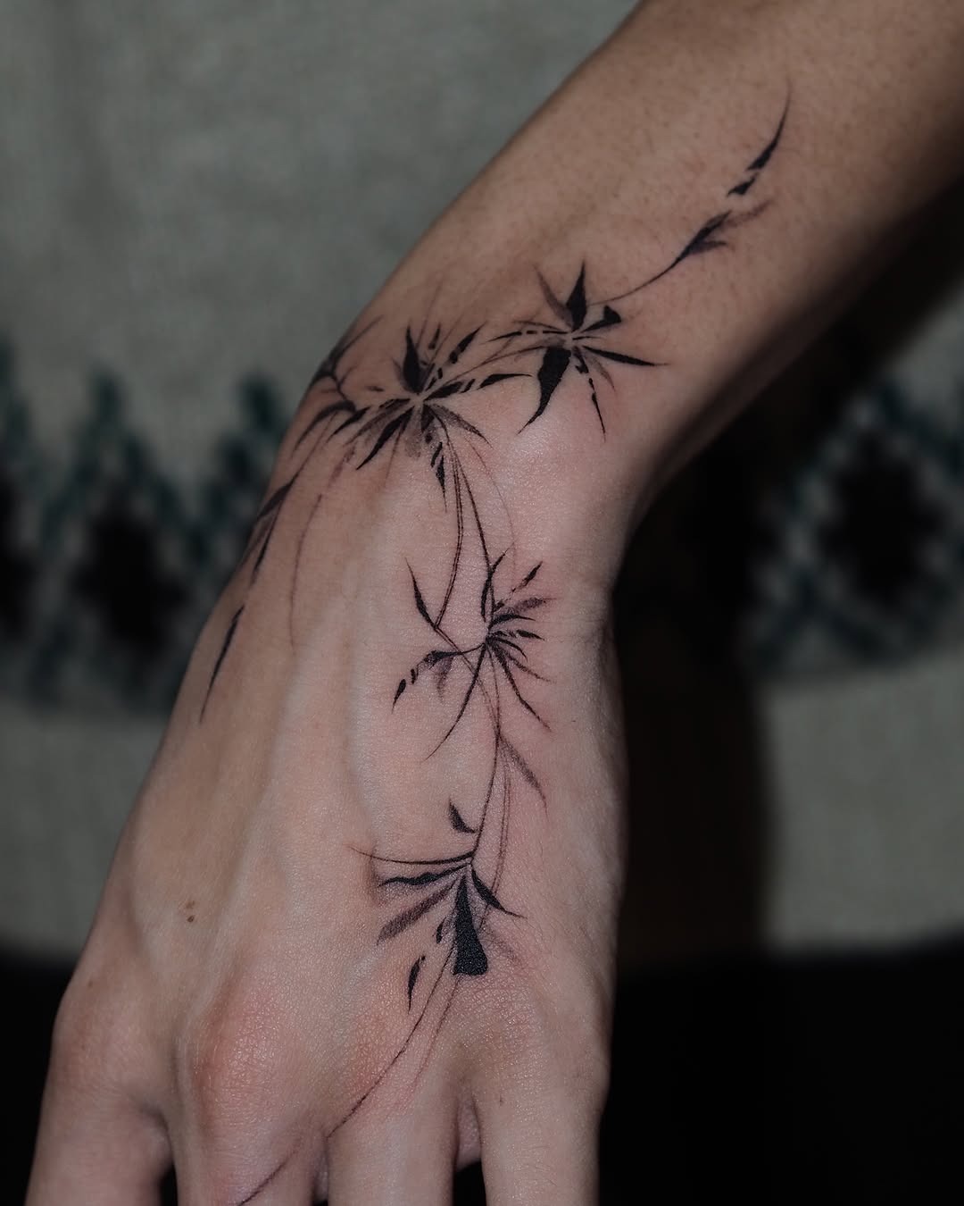 This tattoo showcases a series of elegant, abstract floral patterns inked in black.
