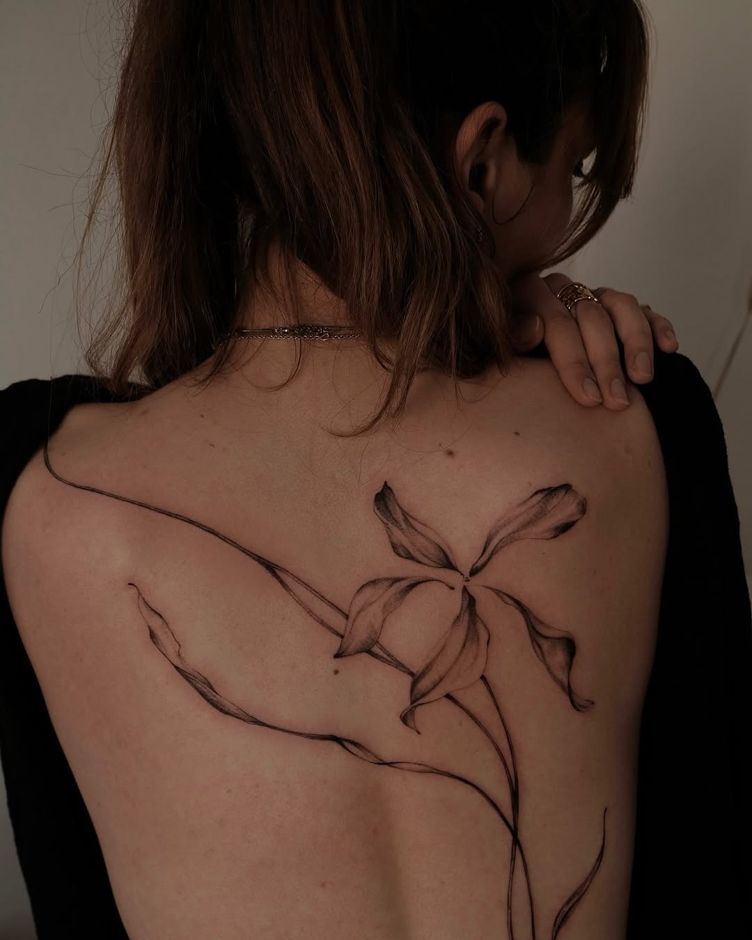 This stunning abstract tattoo features a delicate floral design elegantly tracing the contours of the back.
