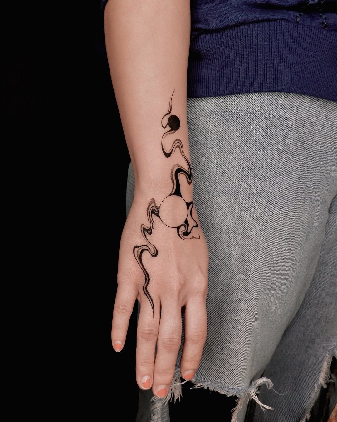This tattoo features a blend of fluid lines and circular shapes, creating an abstract masterpiece on the wearer's forearm.