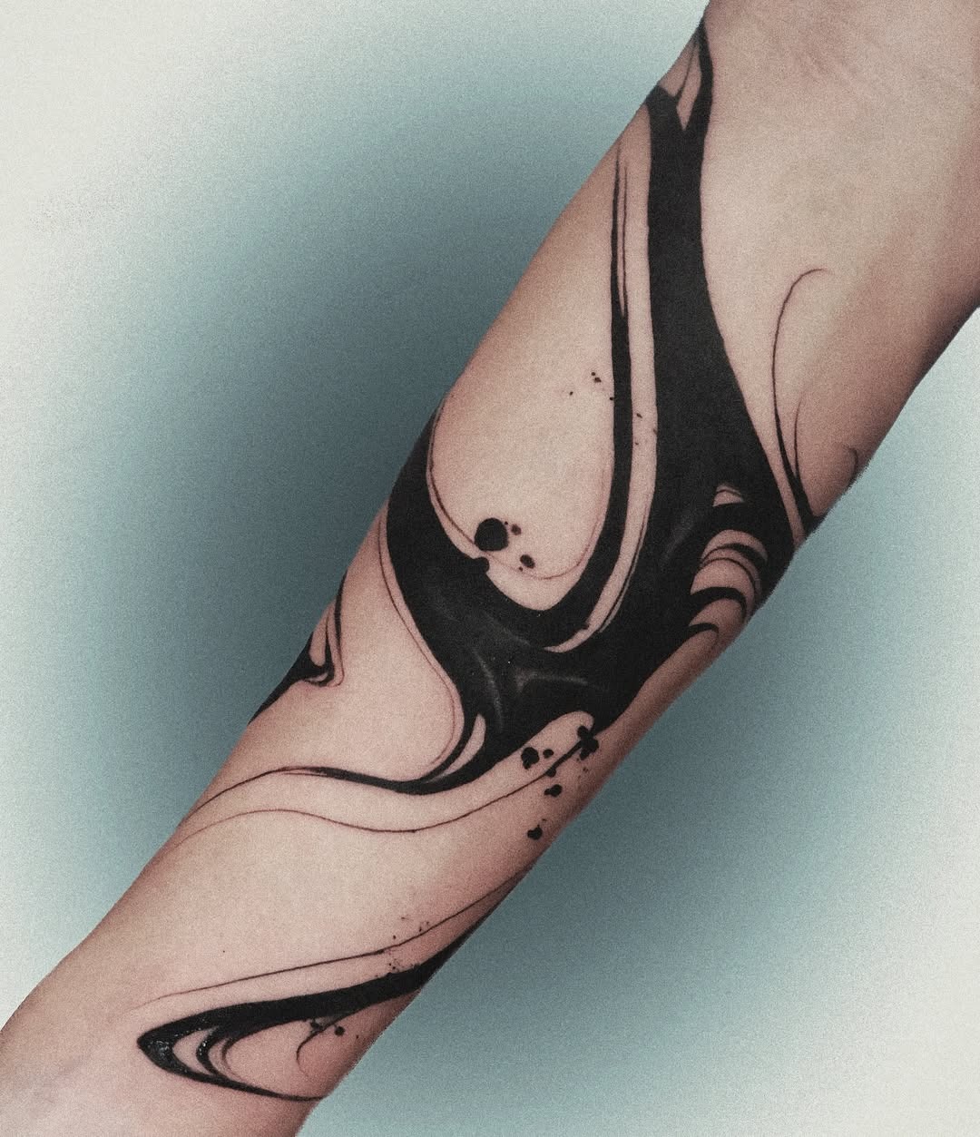 This abstract tattoo showcases fluid black lines that elegantly swirl around the arm.