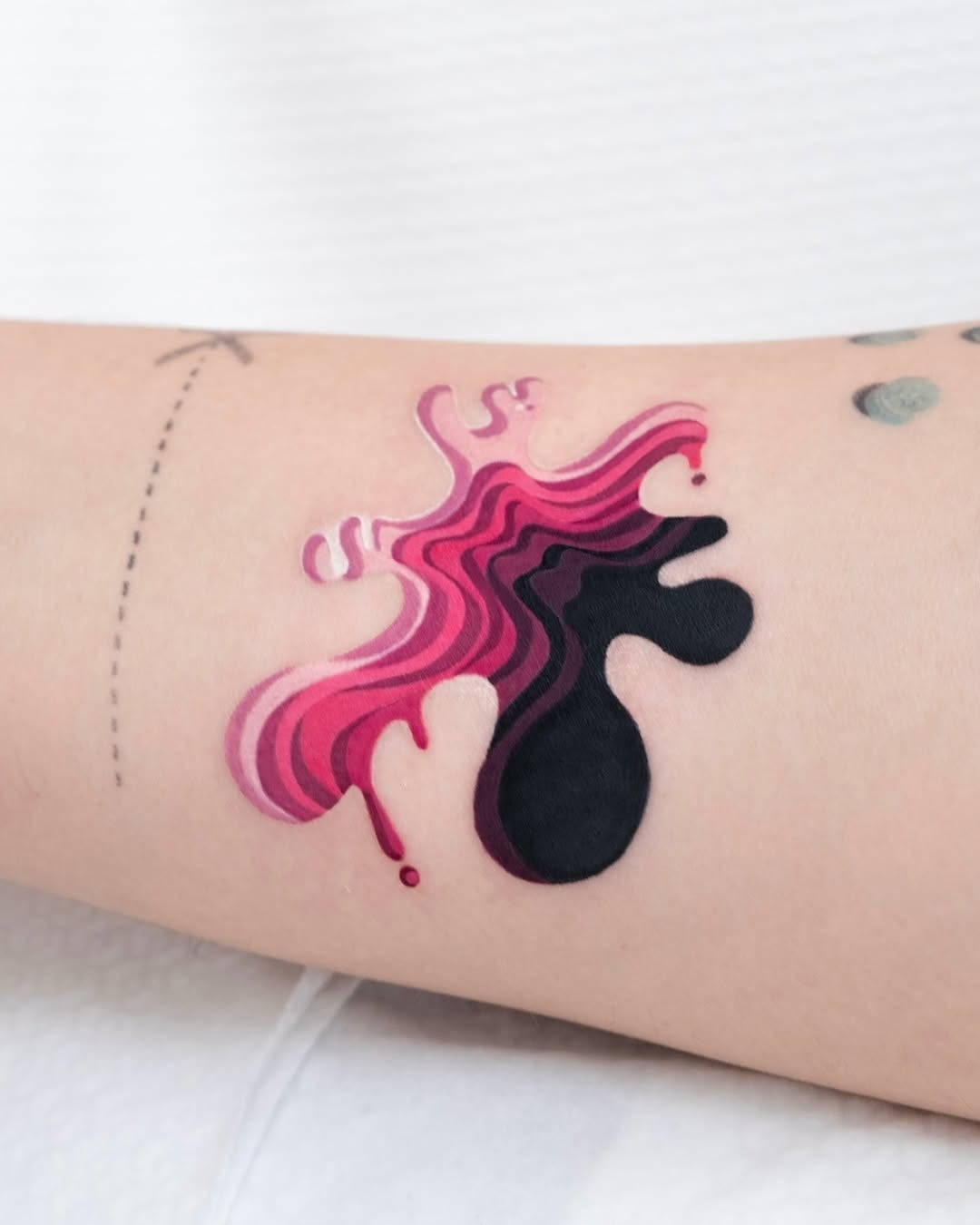 This eye-catching tattoo showcases a splash of pinks and blacks, creating a visually striking piece on the skin.