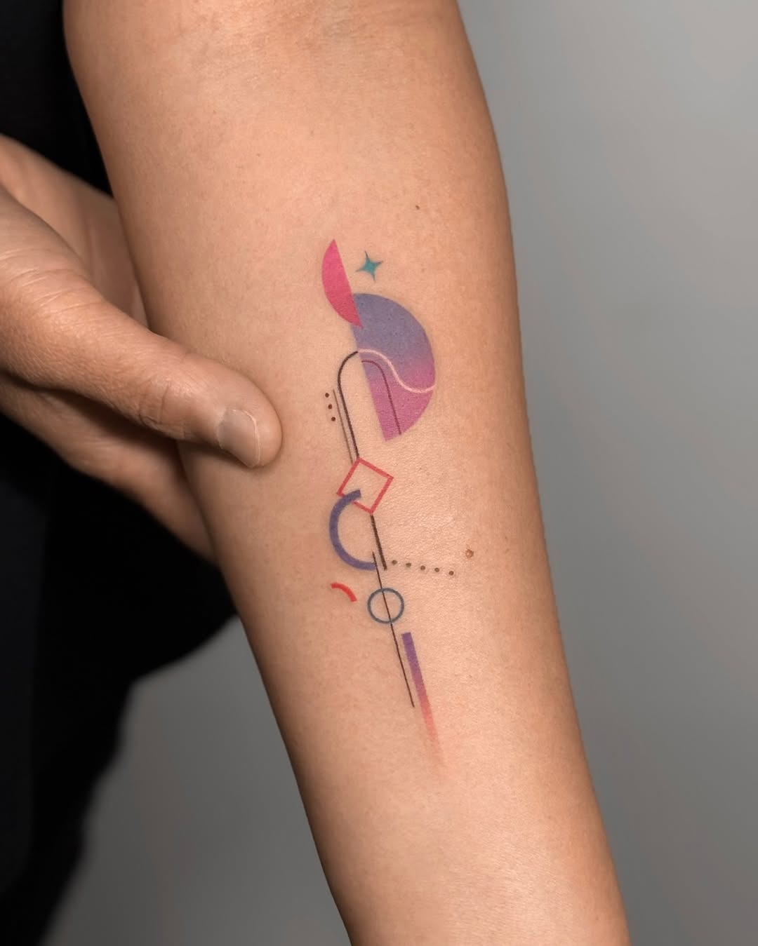 This tattoo showcases a blend of colors and shapes, creating a modern abstract aesthetic.