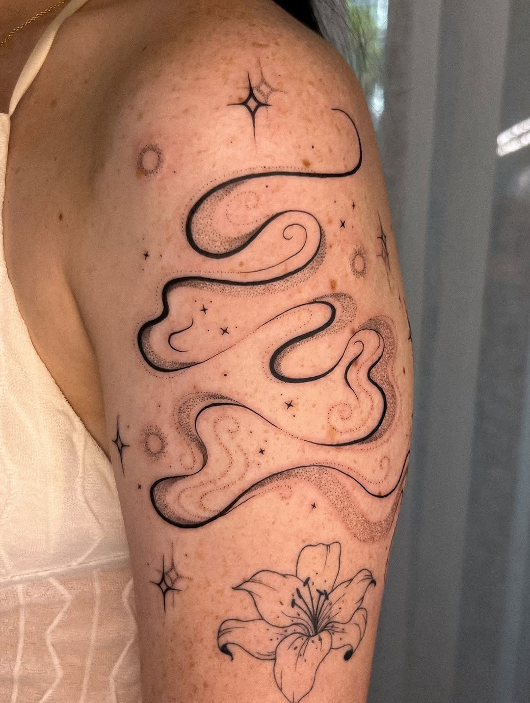 This abstract tattoo features flowing curvy lines that dance across the arm, evoking a sense of movement and fluidity.