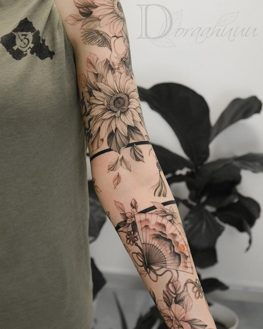 This tattoo showcases a stunning mix of flowers and an ornate hand fan.