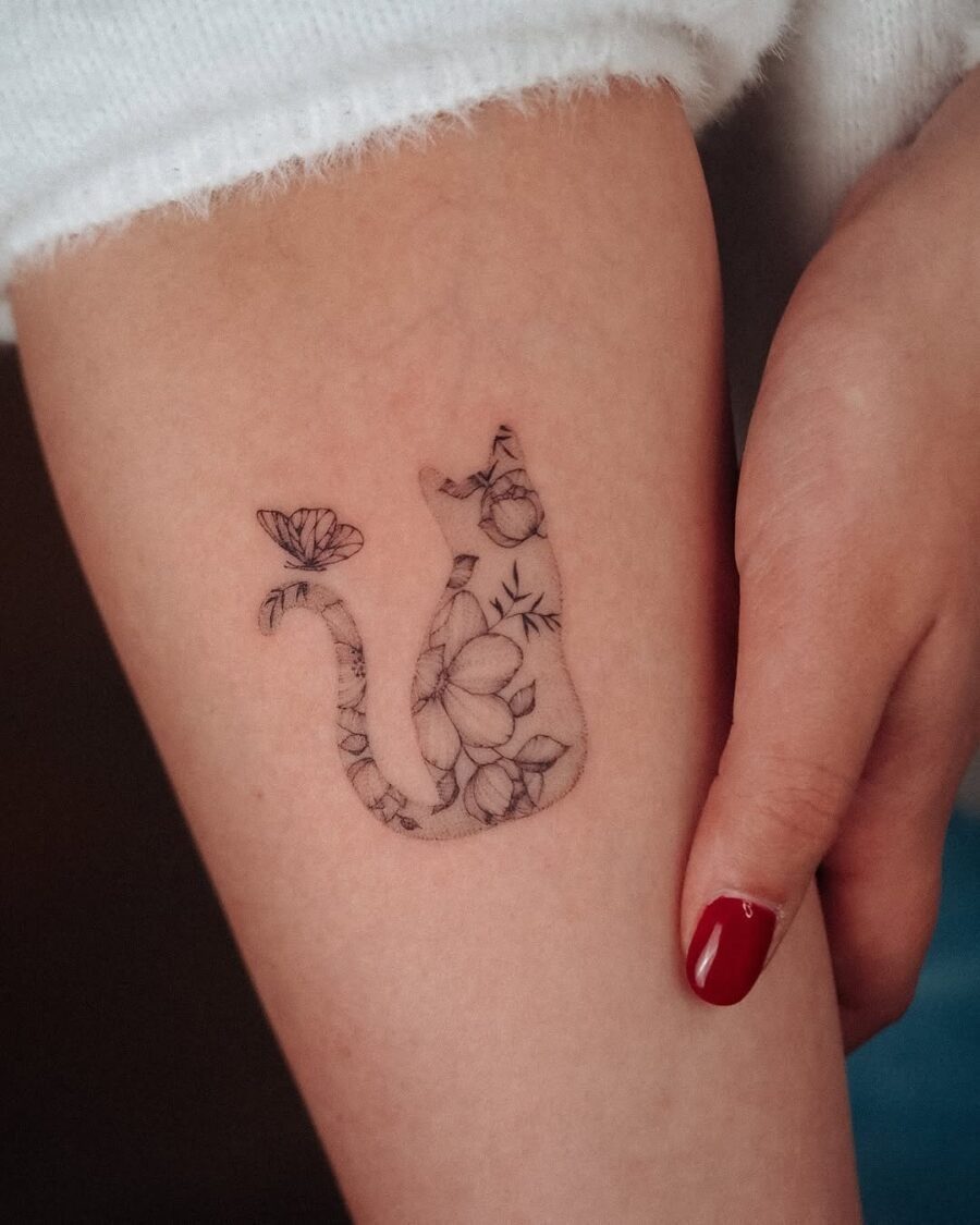 This tattoo features a minimalist design of a cat silhouette filled with floral elements.