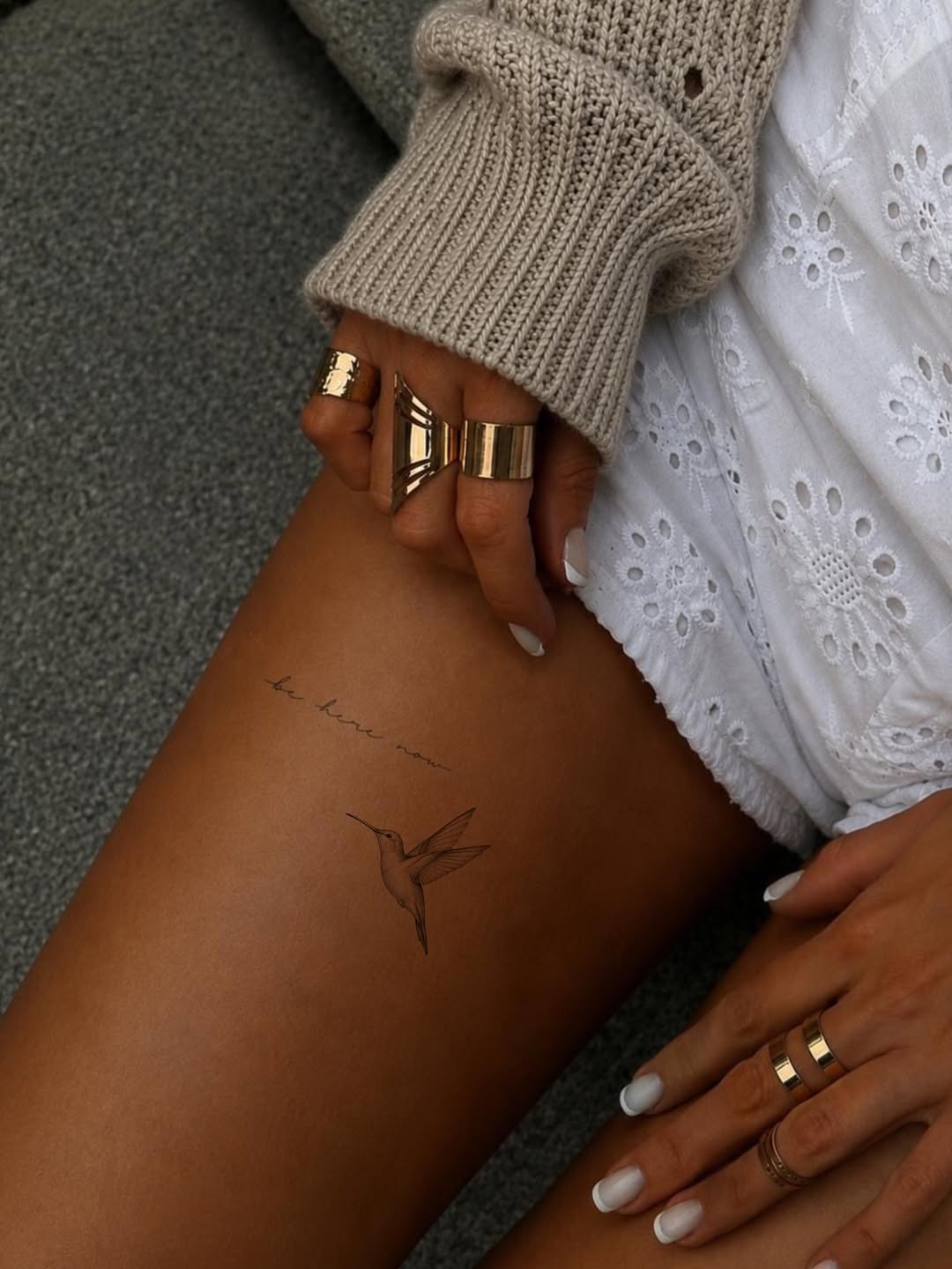 This tattoo features a delicate hummingbird gracefully perched on the thigh.