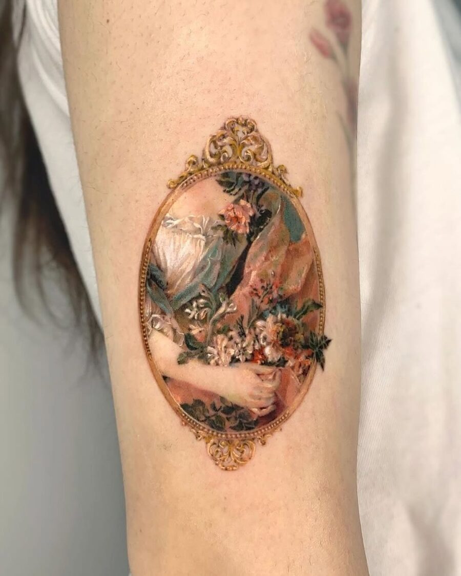 This tattoo is a stunning blend of art and nature, featuring a beautifully detailed floral composition enclosed in an antique frame.