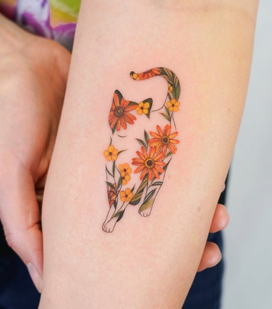 This tattoo features a playful cat silhouette filled with flowers.