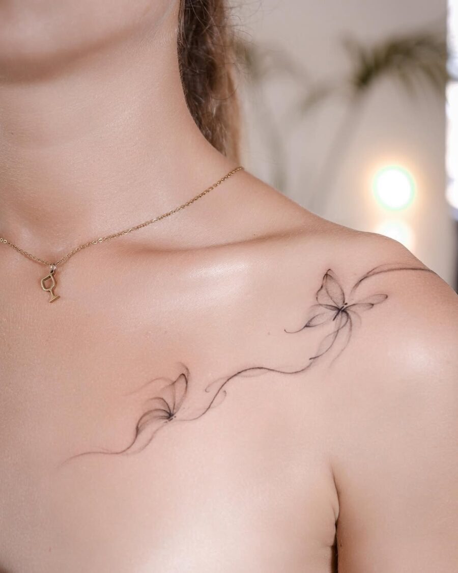 This tattoo features a beautiful and delicate floral design, elegantly inked along the shoulder.
