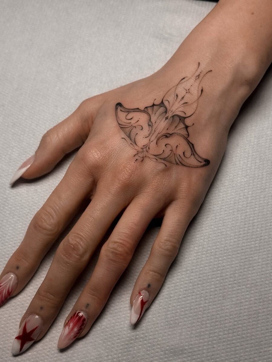 This tattoo features an elaborate floral design on the back of the hand, showing delicate lines and artistic flair.