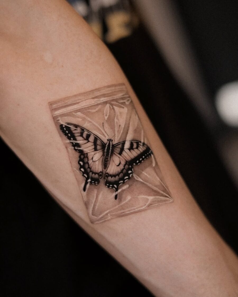 This tattoo showcases a stunning butterfly appearing to be encased in a translucent bag.