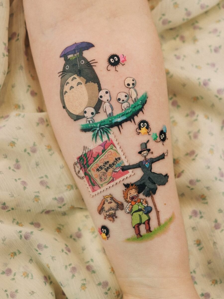 This tattoo showcases a mix of beloved characters from Studio Ghibli, including Totoro and soot sprites surrounded by playful elements.