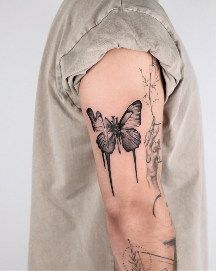 This black butterfly tattoo features intricate detailing and creative drip effects, adding an edgy vibe.