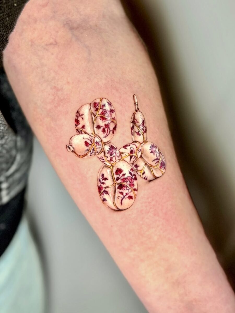 This whimsical tattoo features a playful balloon dog adorned with delicate floral elements.