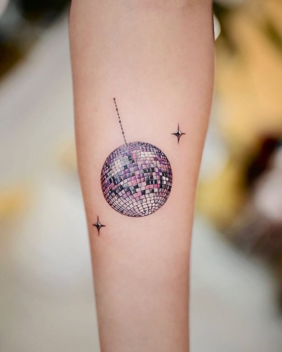 This tattoo showcases a disco ball nestled on the forearm, radiating fun and nostalgia.