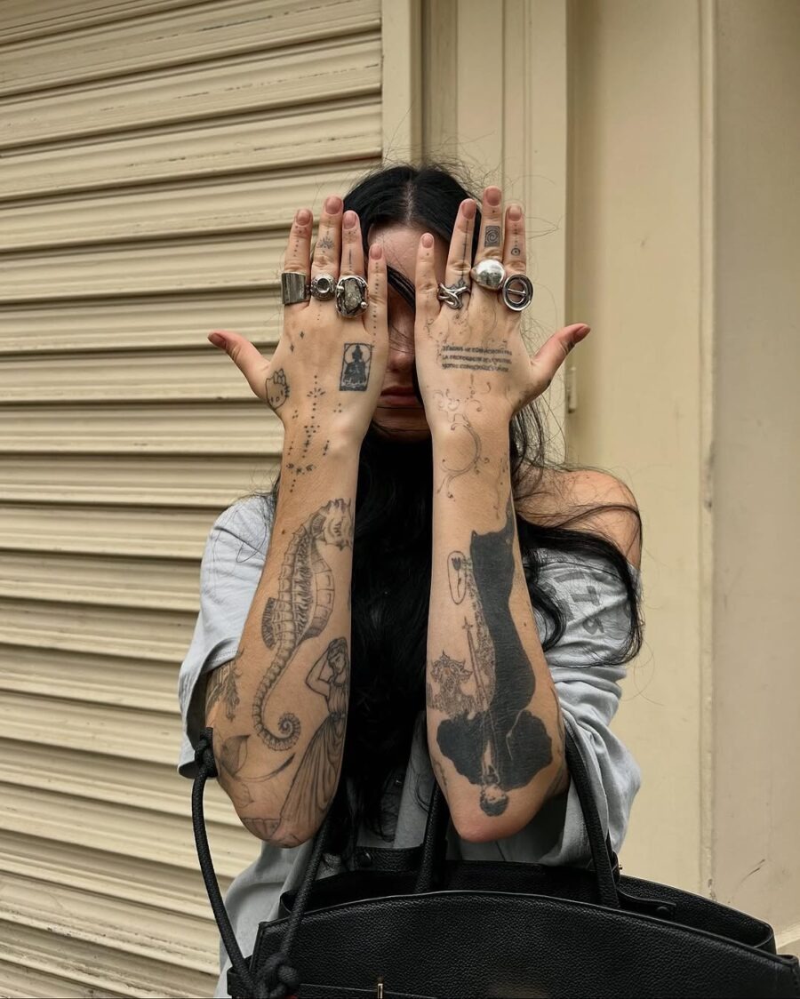 This image showcases a person with intricate tattoos covering their arms, featuring a seahorse and stars.