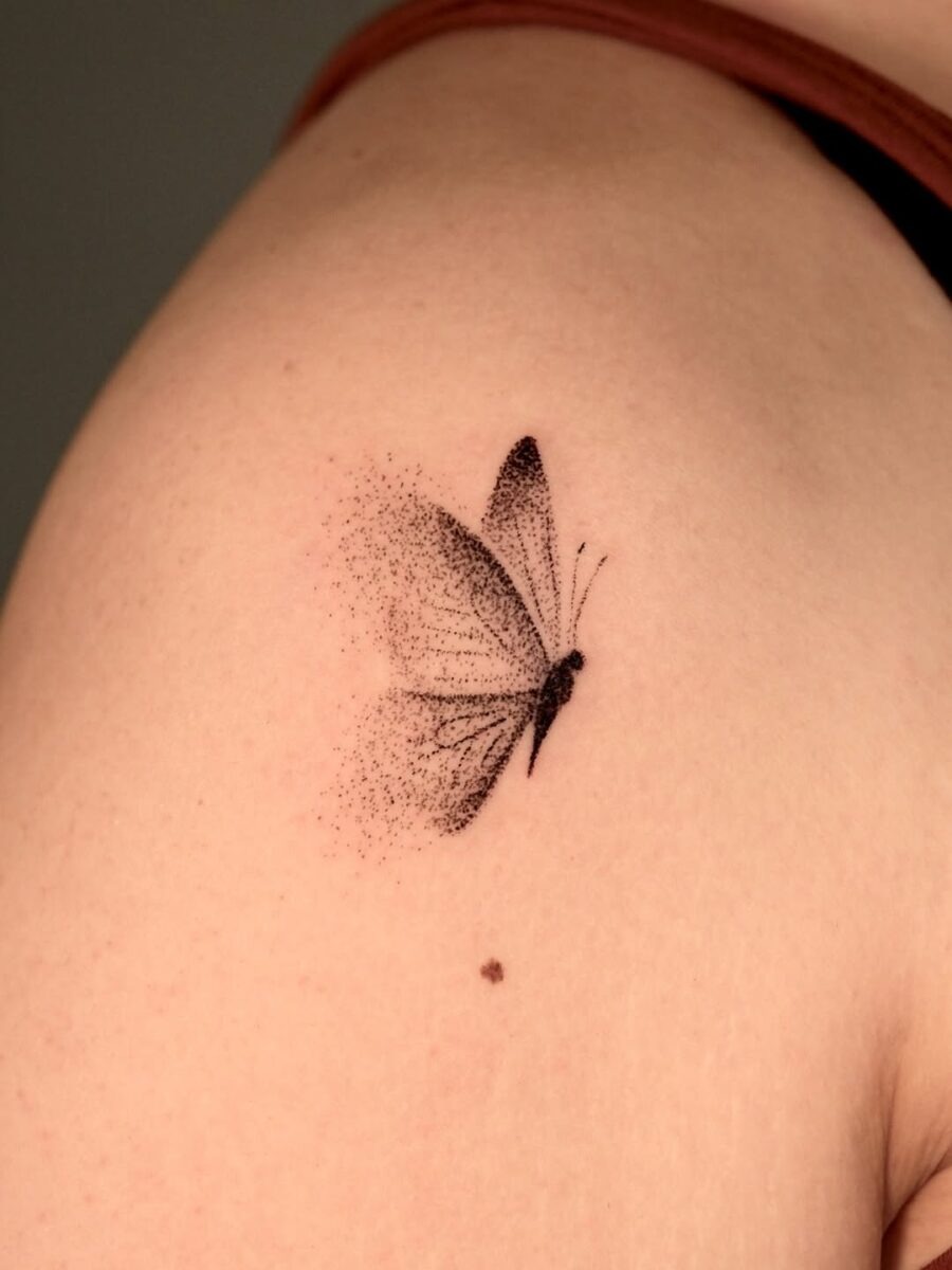 This aesthetic tattoo features a delicate butterfly rendered in minimalist black ink.