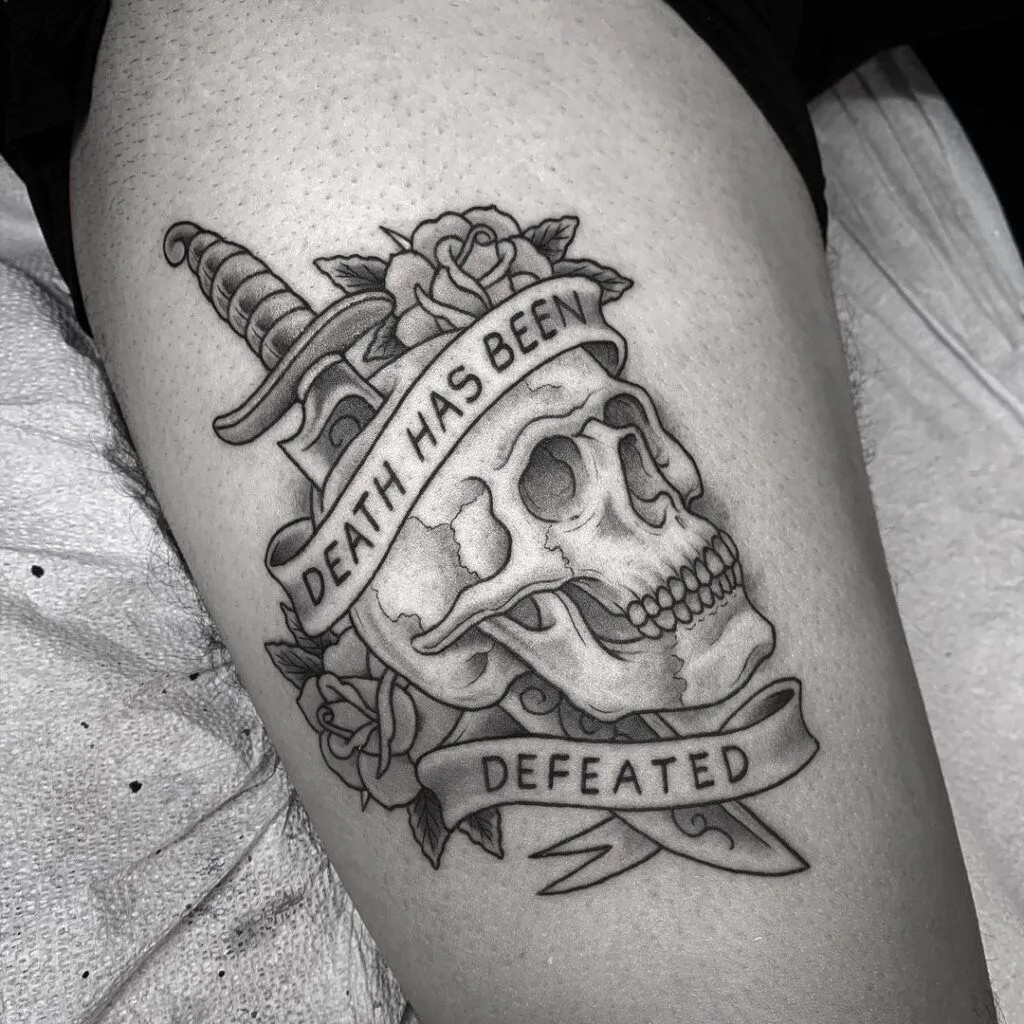 American traditional skull tattoo with banner and blood red rose on forearm