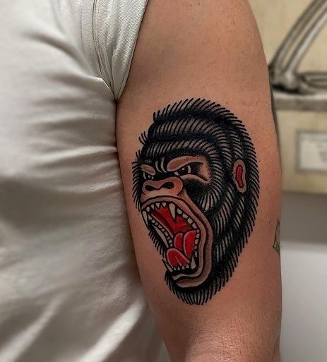 American traditional gorilla tattoo with snarling teeth and jungle floral accents