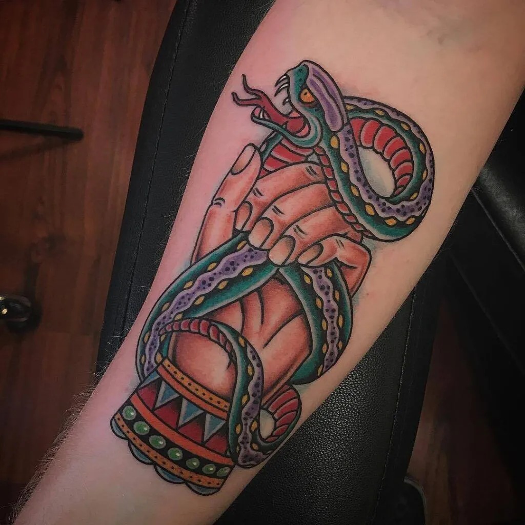 American traditional coiled snake tattoo wrapping around the wrist with bared fangs