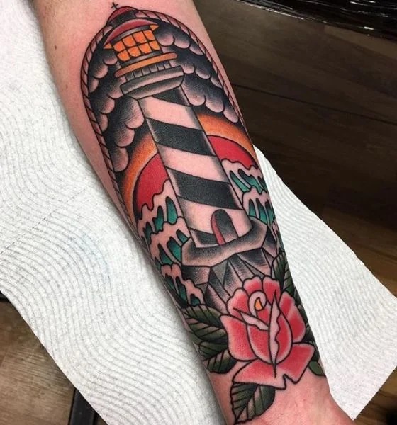 American traditional lighthouse tattoo standing tall on jagged cliffs with storm waves