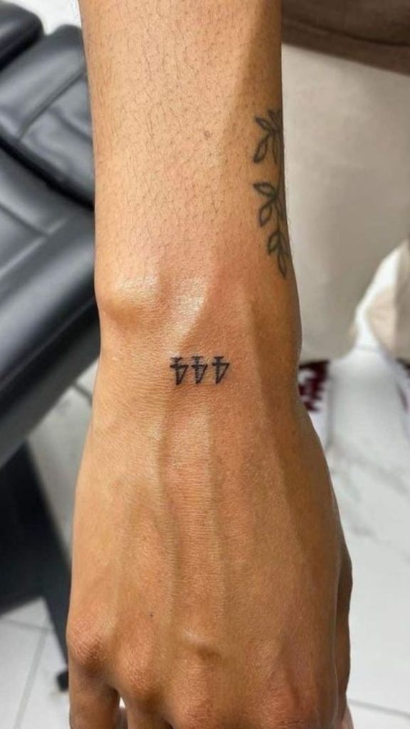 Tiny yet powerful, this micro tattoo uses three mini bolts shaped like 4s, a creative deviation from traditional fonts.