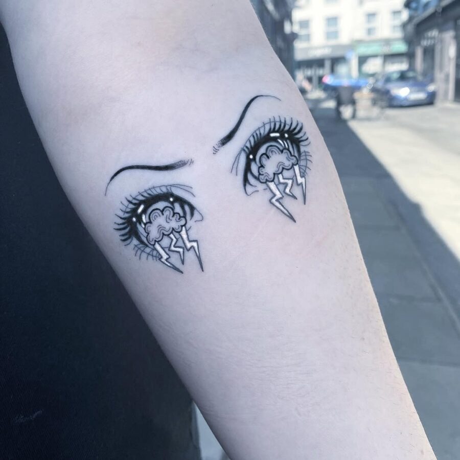 This tattoo features striking anime eyes, each adorned with long lashes and dramatic eyebrows.
