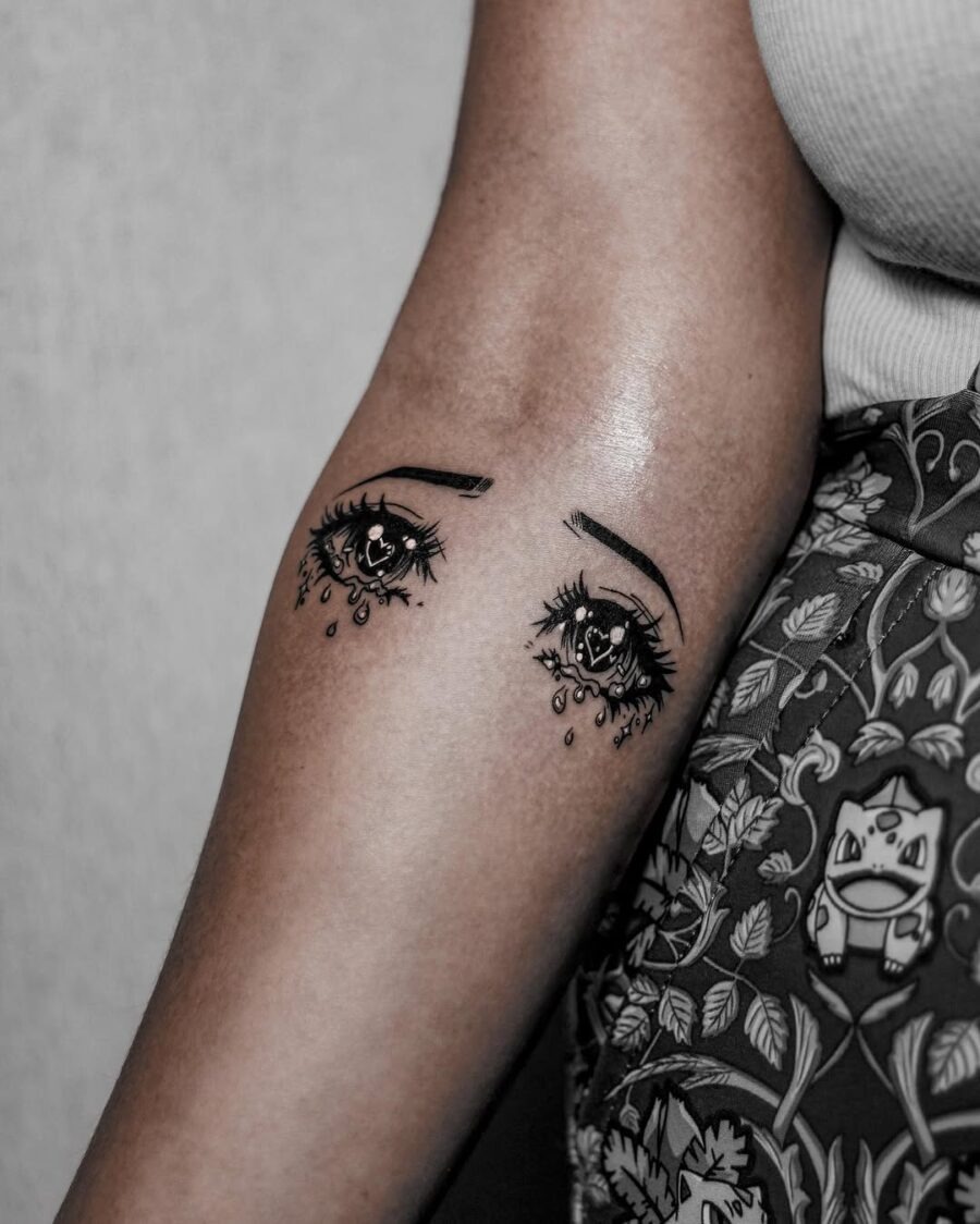 This tattoo showcases a pair of anime-style eyes, intricately detailed with tears cascading down.