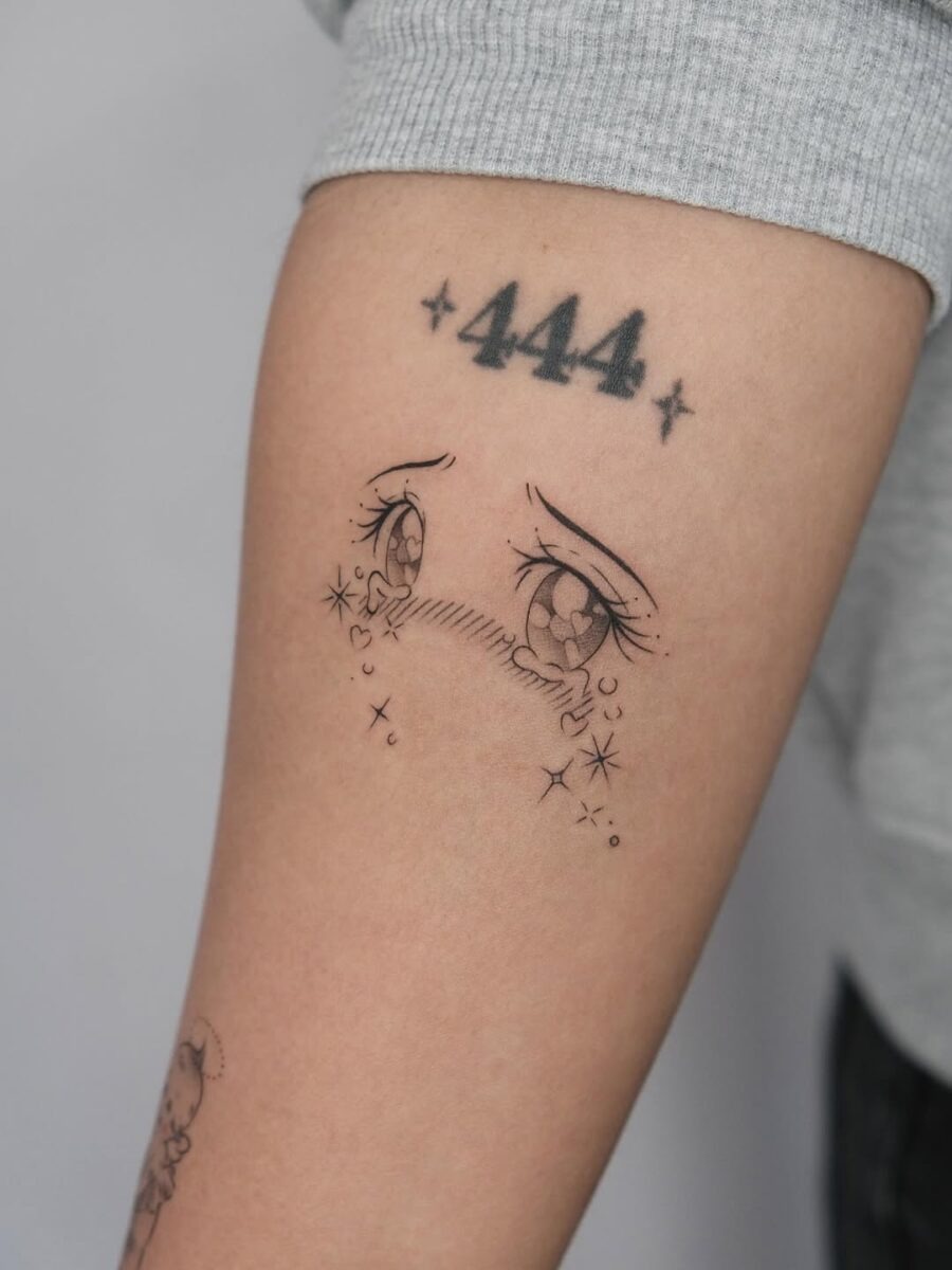 This tattoo features intricately designed anime eyes with a melancholic expression.