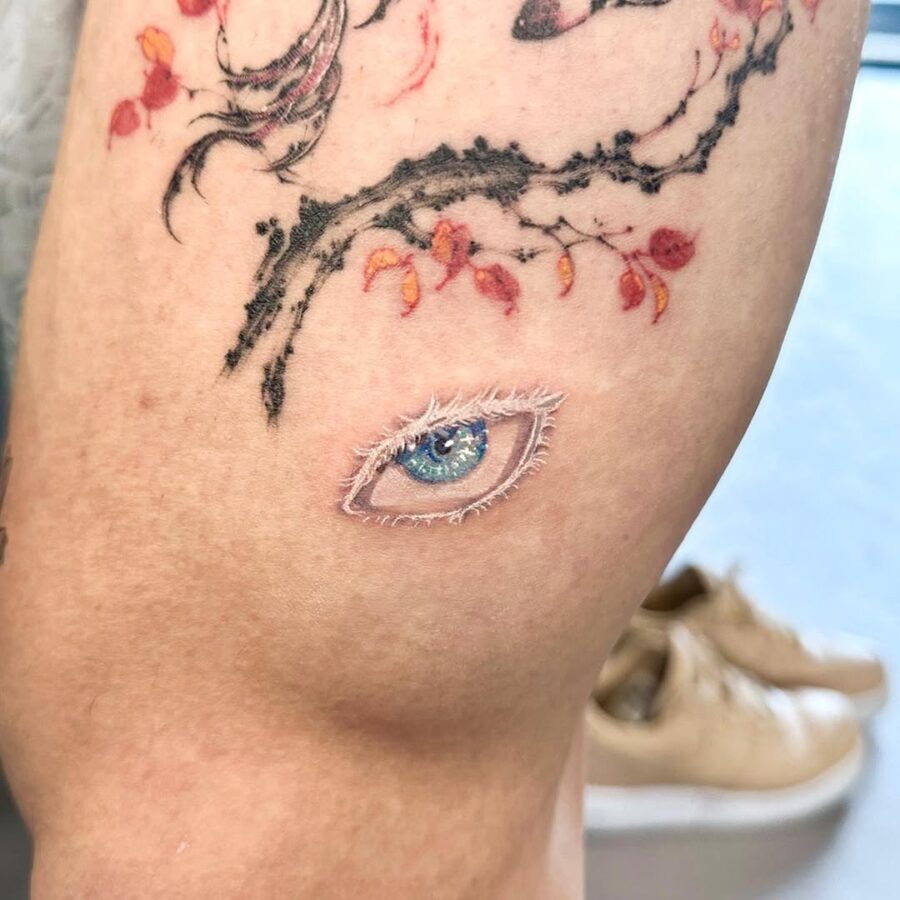 This tattoo features a beautifully detailed anime eye, complete with colors and striking textures.