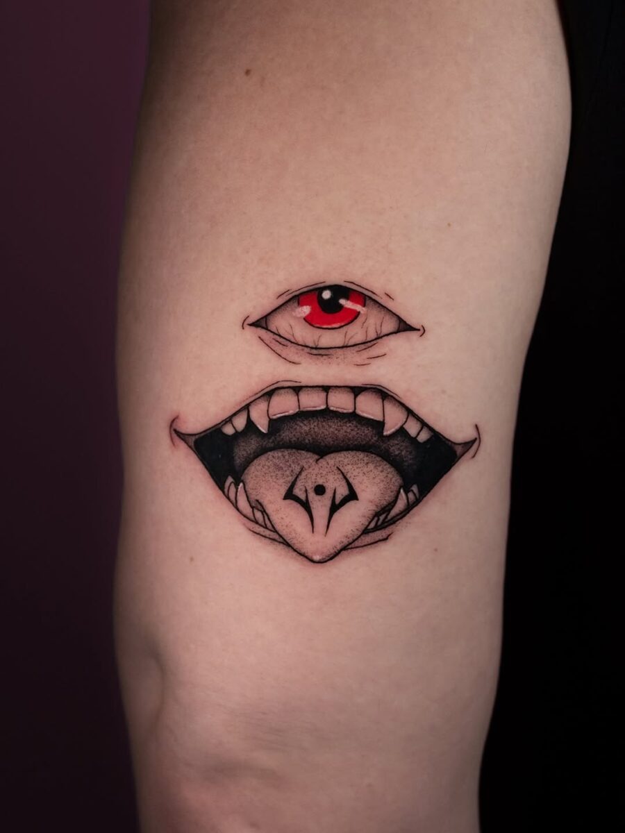 This tattoo features a striking red eye above a mouth, creating a surreal and intriguing visual.