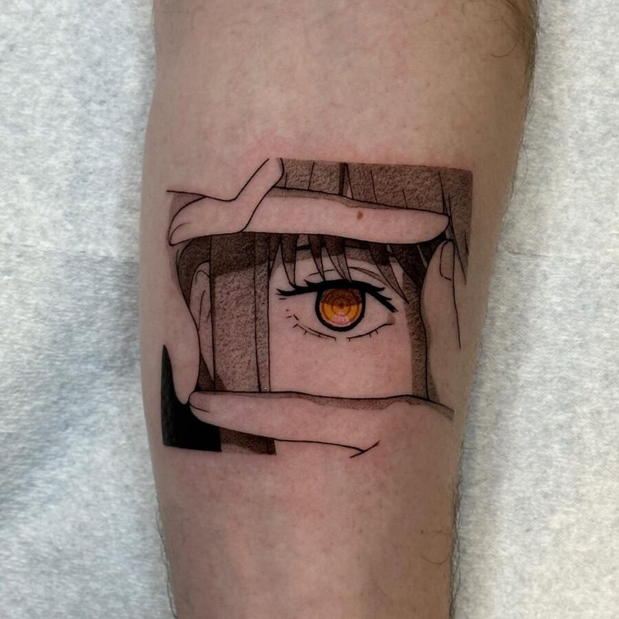 This tattoo features a striking anime eye nestled within a frame created by hands, blending realism and creativity.