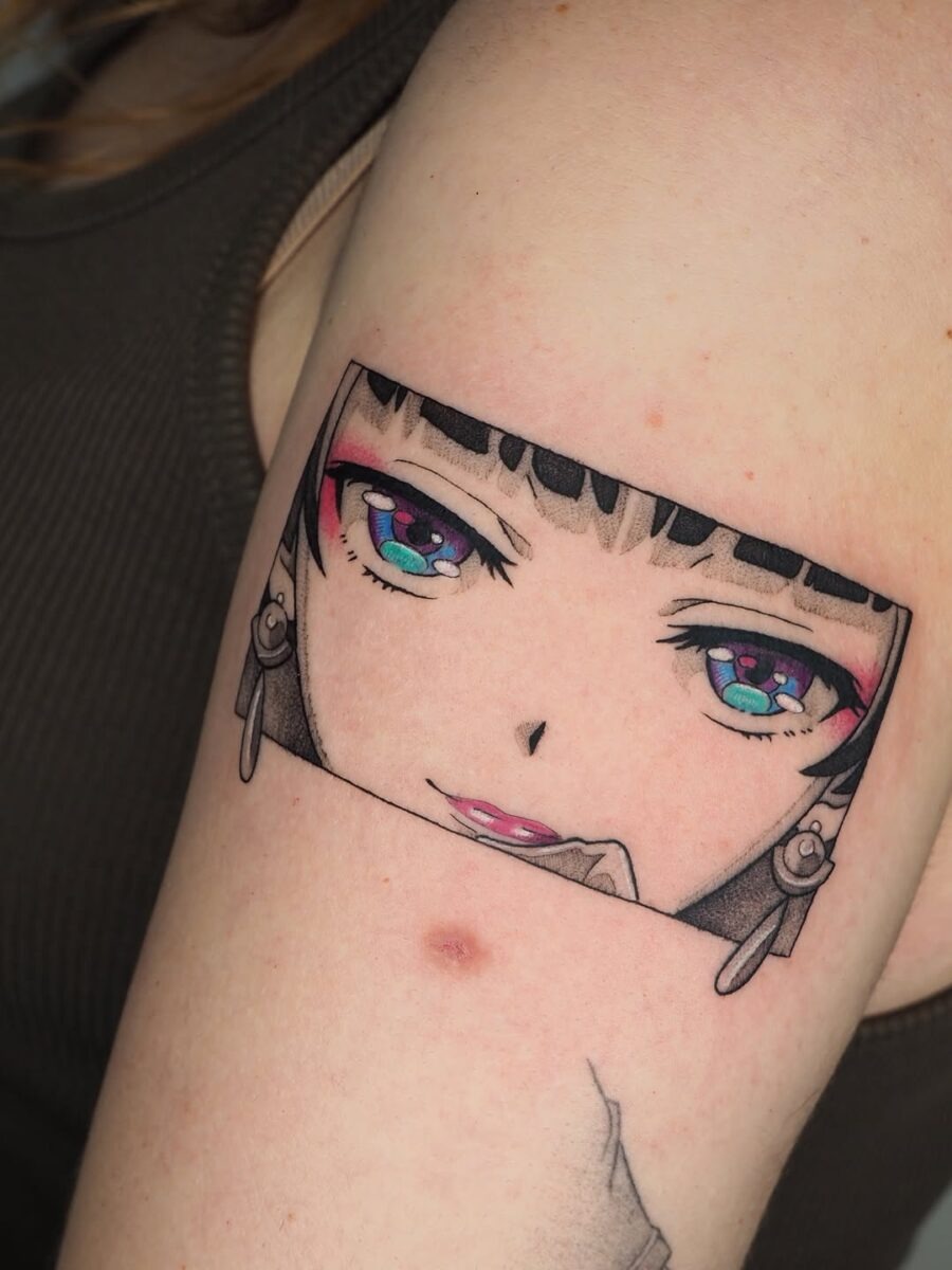 This tattoo features a beautifully detailed anime character with striking eyes and a playful smile.