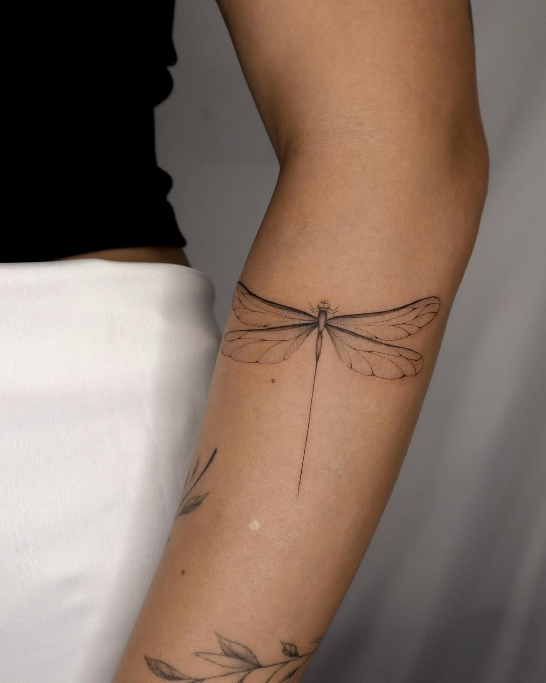 Elegant black ink dragonfly tattoo on arm Tattoo Design