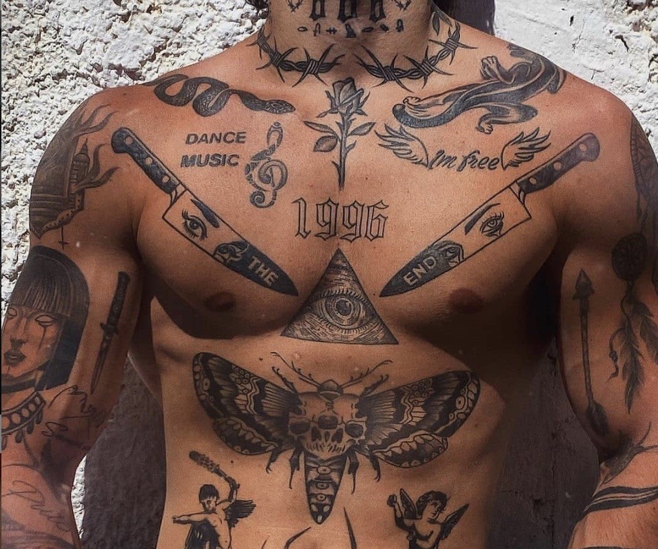 This eclectic chest tattoo collection is a fascinating blend of different styles and symbols, ranging from a death's-head moth to daggers, snakes, and geometric shapes.