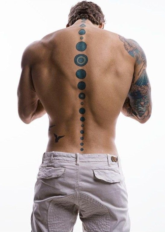 This minimalist spine tattoo features a series of geometric circles arranged vertically along the spine, creating a visually striking design.