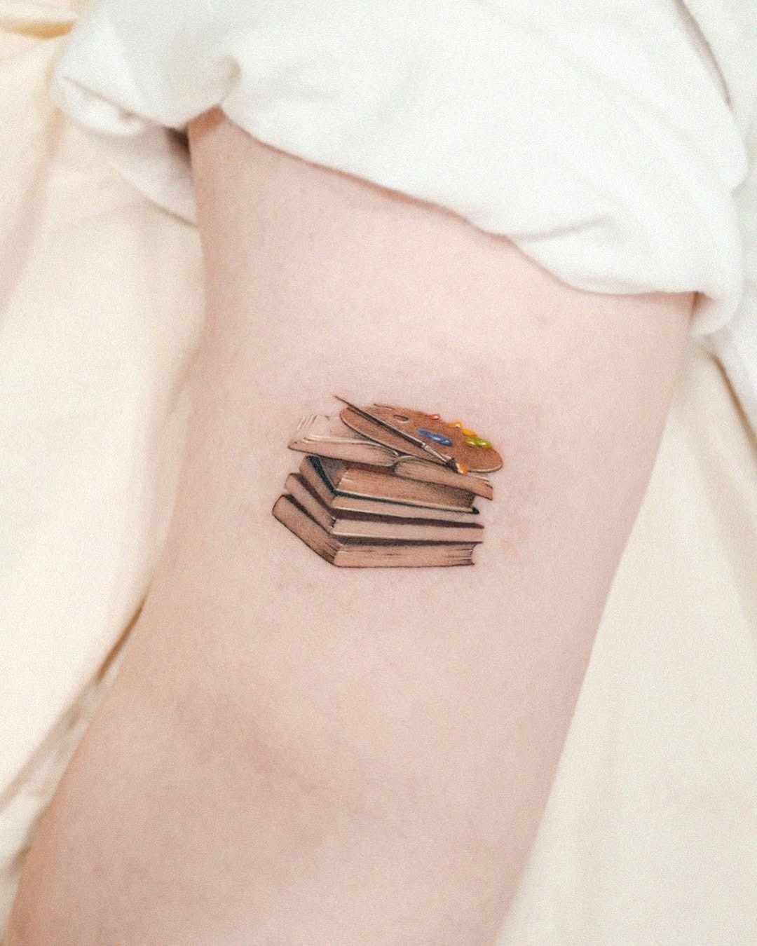 Whimsical stacked books tattoo design on skin Tattoo Design