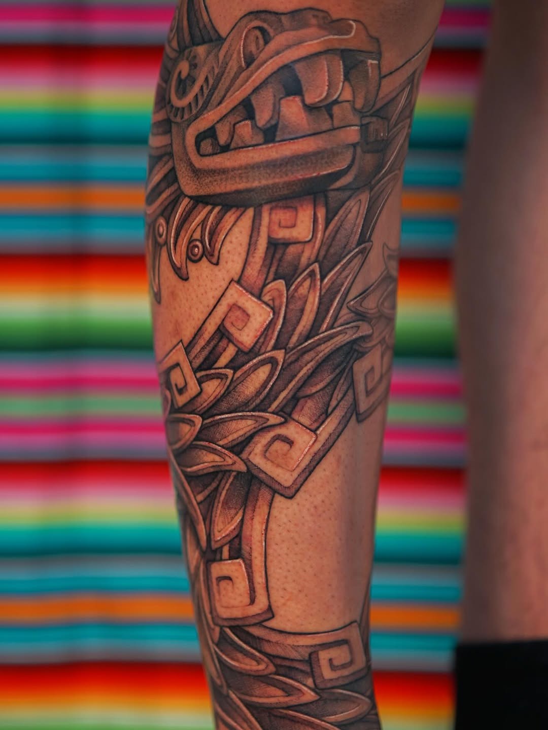 Intricate Aztec leg tattoo with vibrant backdrop Tattoo Design