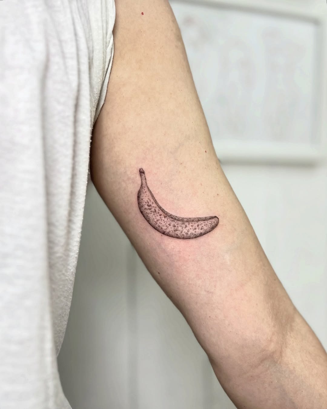This banana tattoo features a sleek, minimalistic design, showing a playful yet artistic depiction of the fruit.