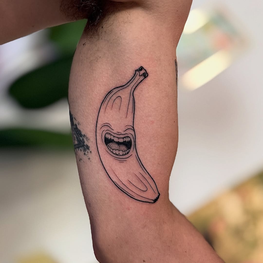 This tattoo features a playful banana with a big, joyful grin, perfectly capturing a fun-loving spirit.