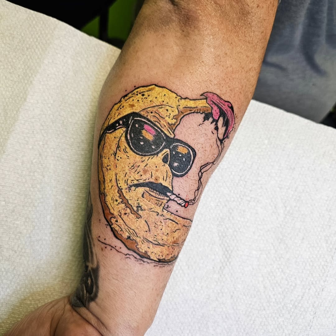 This funky banana tattoo features a slice wearing sunglasses and casually smoking.