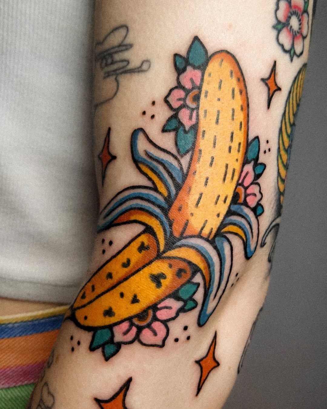This tattoo features a playful banana surrounded by lovely flowers.
