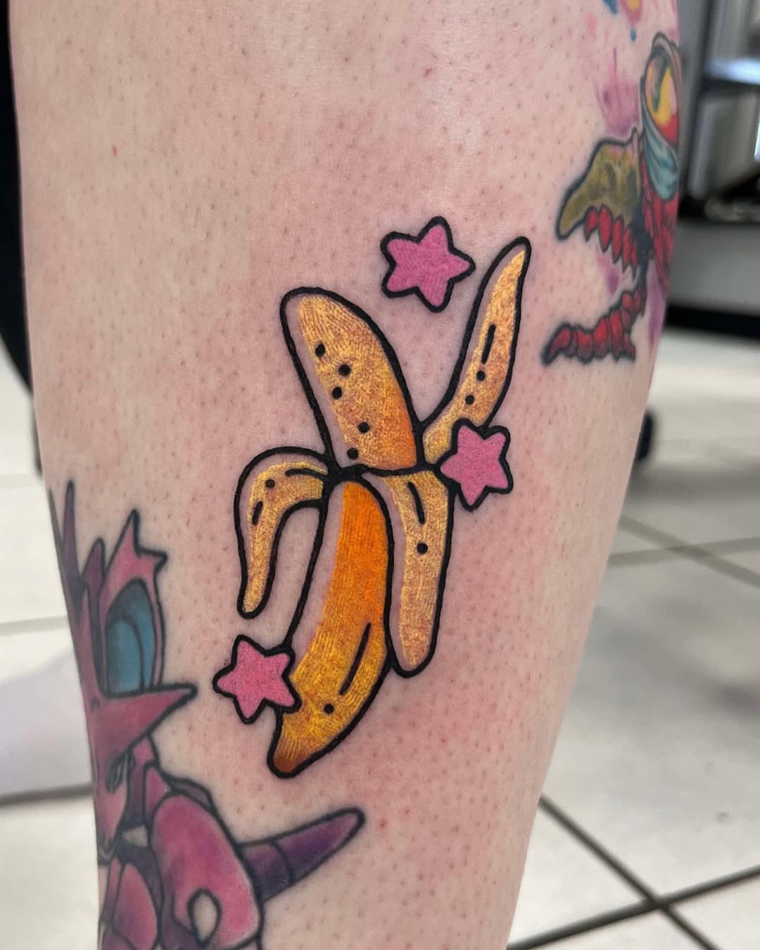 This fun banana tattoo features a bright yellow banana adorned with cute pink stars.