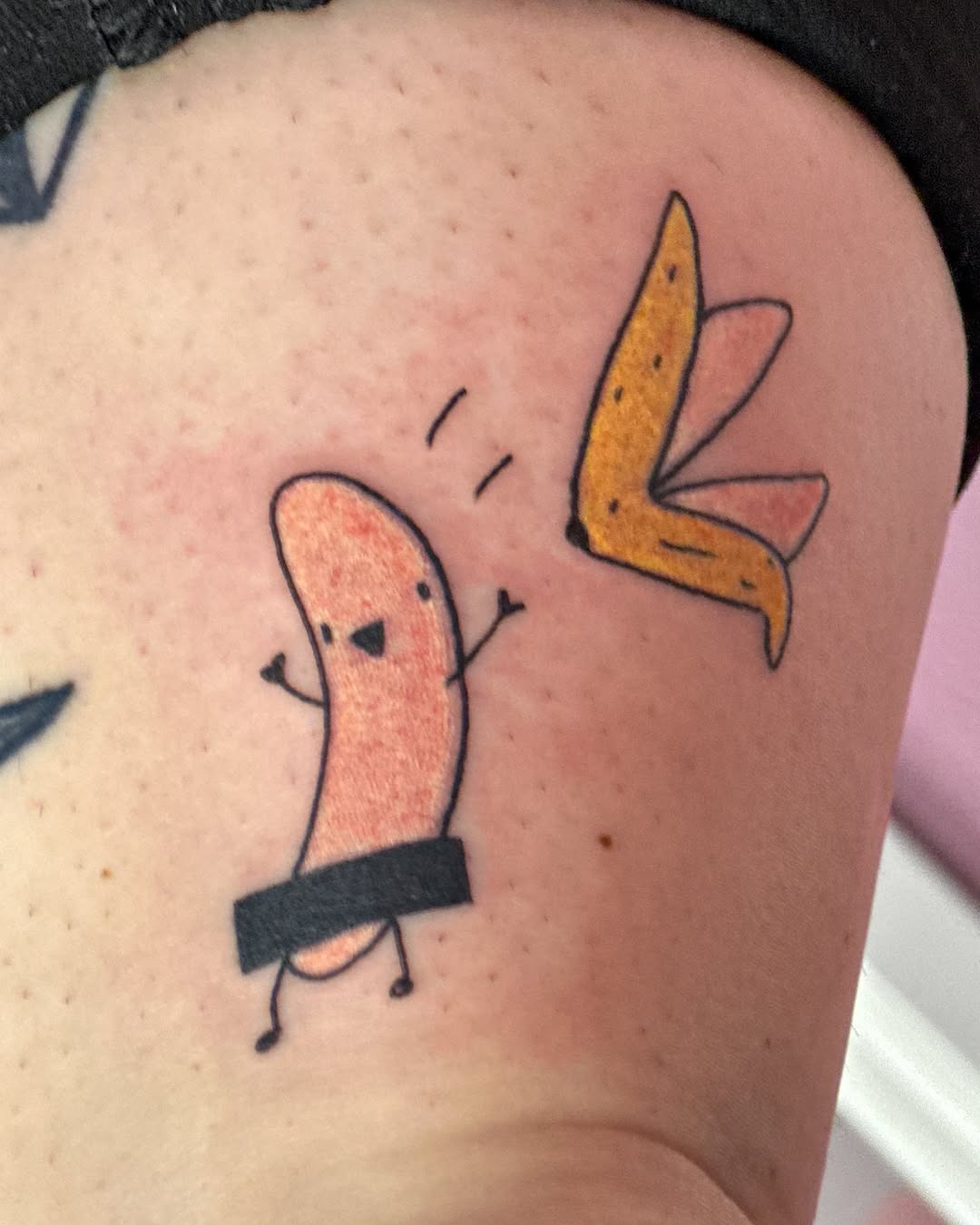 This tattoo features a fun cartoon-style banana alongside a quirky character.