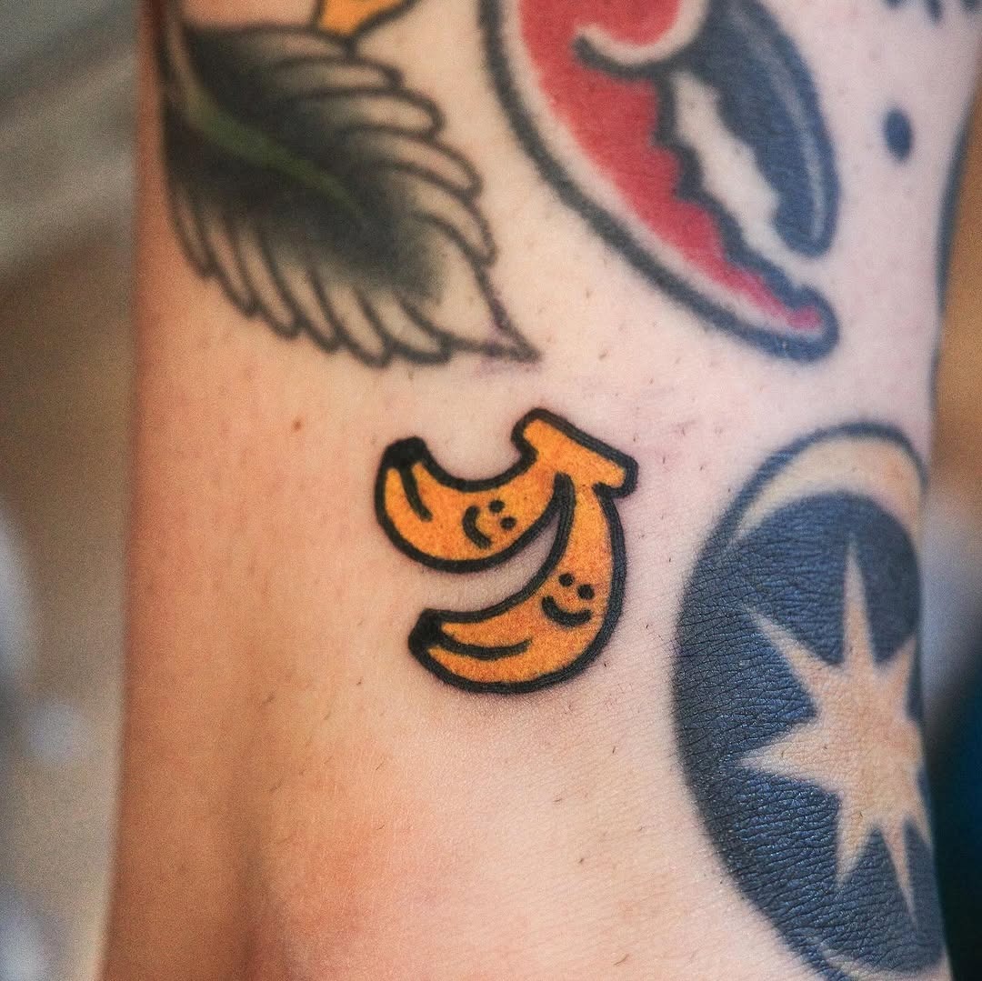 This tattoo features two cheerful bananas, each adorned with a smiling face.