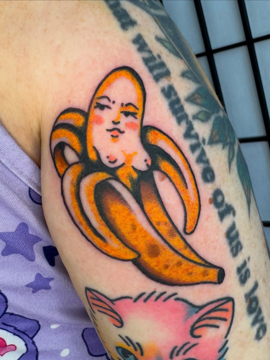 This tattoo features a playful, cartoon-style depiction of a banana with a whimsical character.