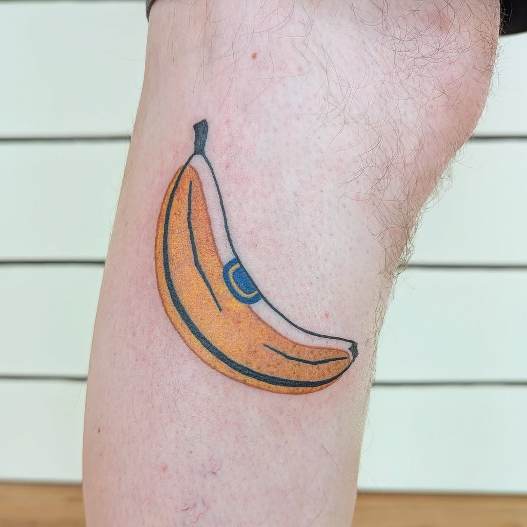 This tattoo features a bright yellow banana, radiating a sense of fun and whimsy.