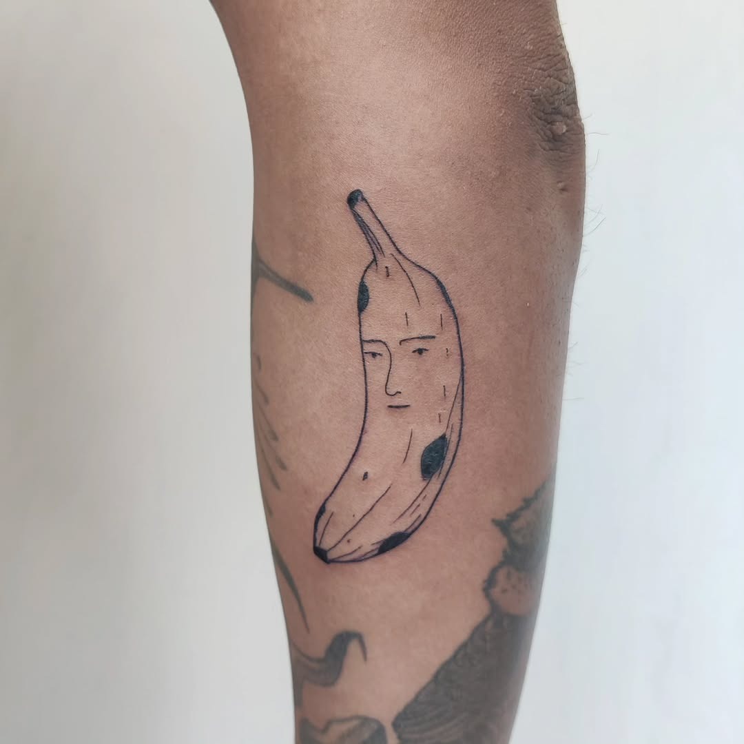 This tattoo features a banana character with a quirky expression.