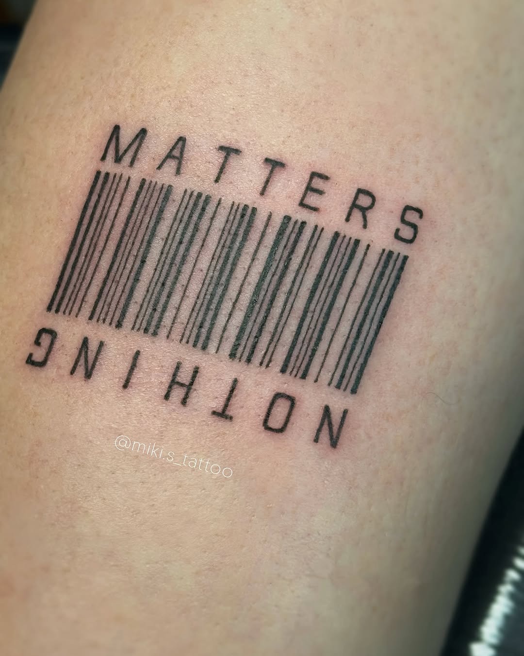 This tattoo features a bold barcode design with the phrase 'MATTERS NOTHING' elegantly integrated above it.